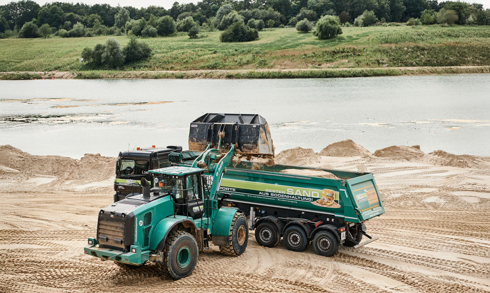 Bagger befüllt Container mit Sand; Sigrun Strangmann Photography